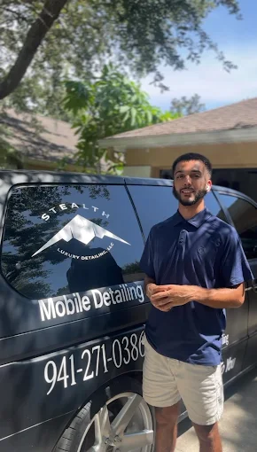 Picture of the owner of Stealth Luxury Detailing, with a black detailing van behind