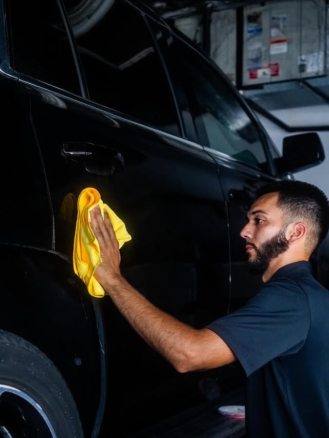 Detailer cleaning surface of black SUV in Sarasota, FL